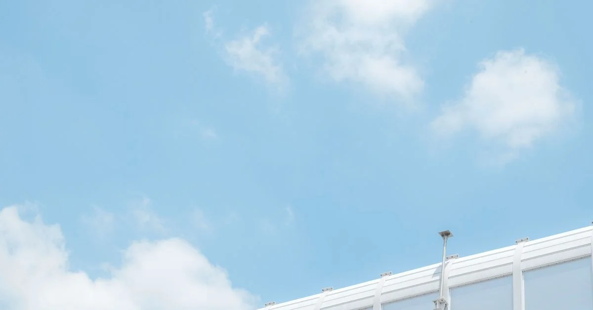 Image minimaliste d'une caméra de sécurité contre un ciel bleu vif avec des nuages épars.