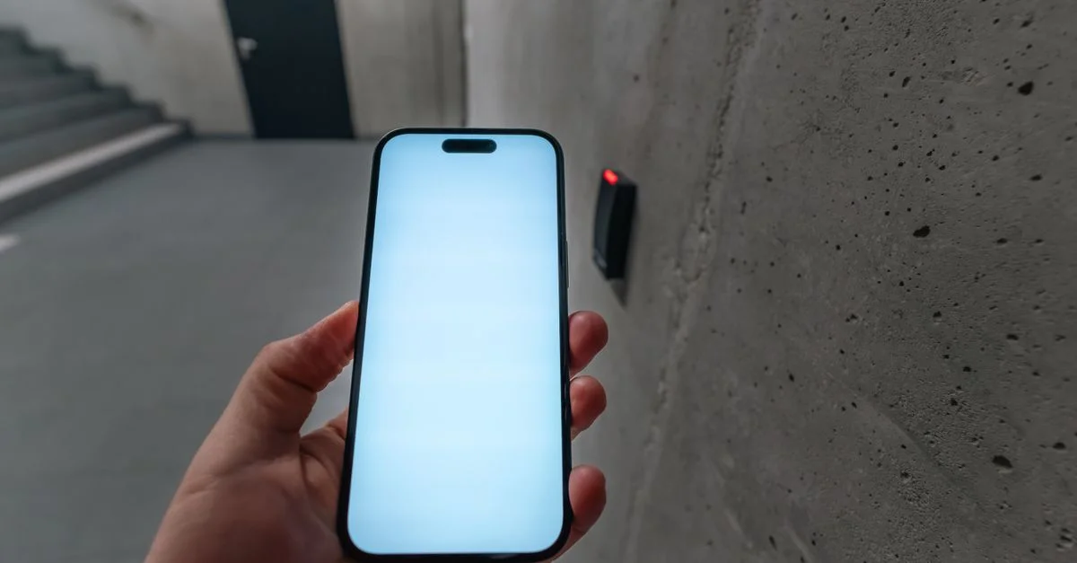 Un smartphone déverrouillant une porte sécurisée à l'aide de la technologie NFC dans la cage d'escalier d'un immeuble moderne.
