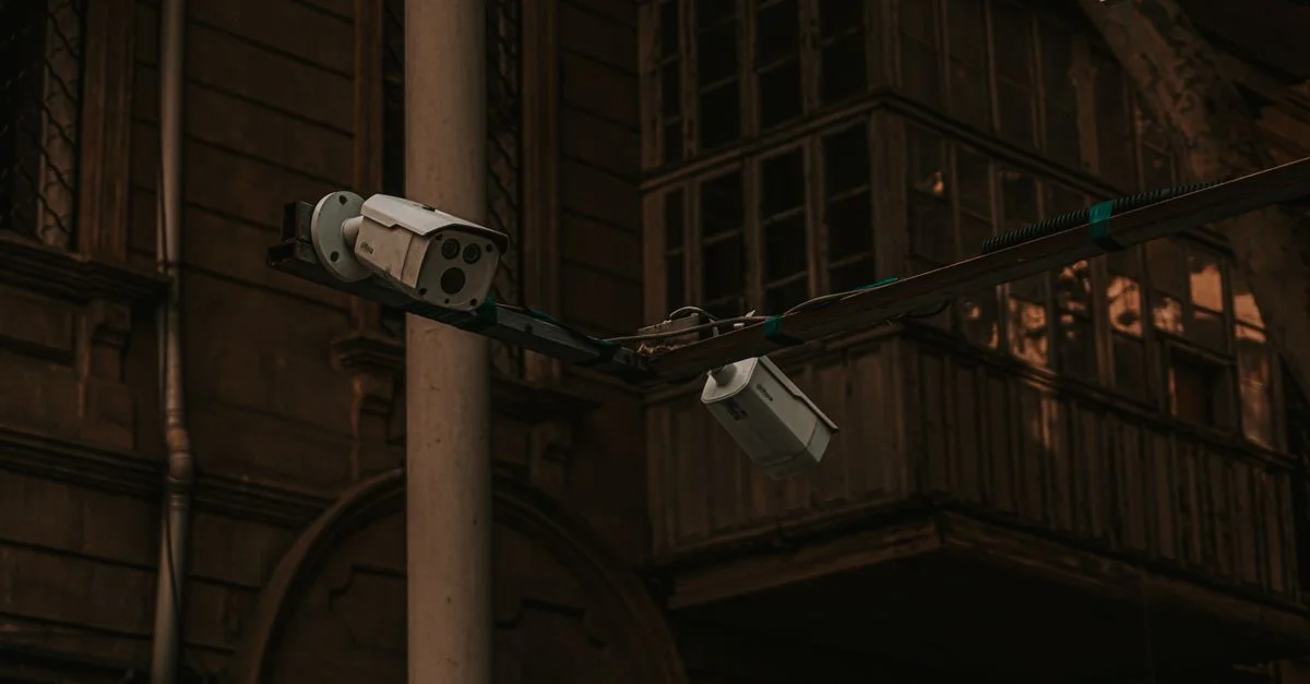 Cameras de sécurité de rue montées sur un poteau dans un environnement urbain, mettant en avant la surveillance.