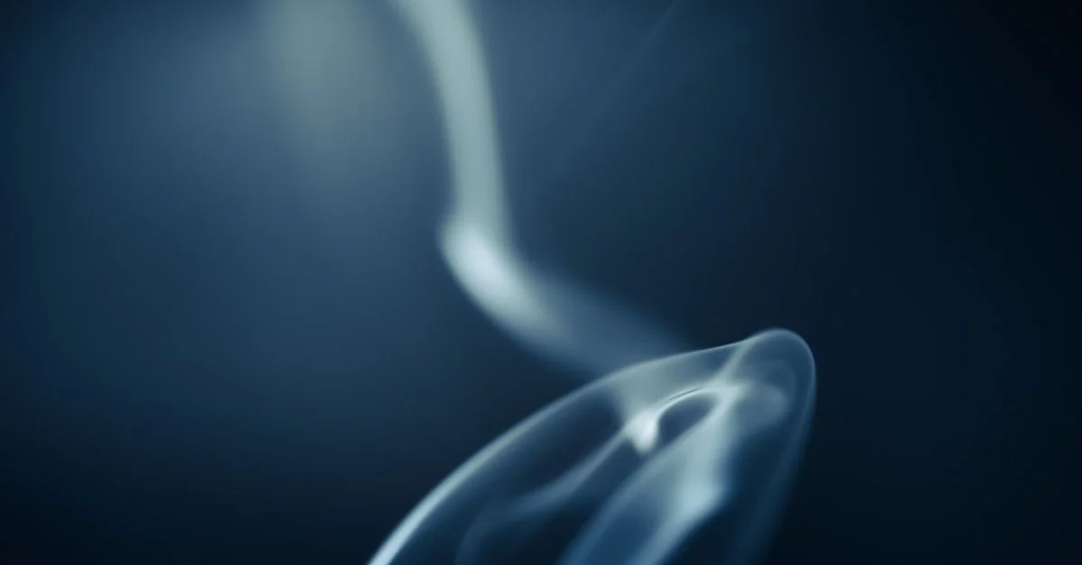 Gros plan abstrait d'un tourbillon de fumée éthérée sur un fond bleu, créant une atmosphère rêveuse et mystérieuse.